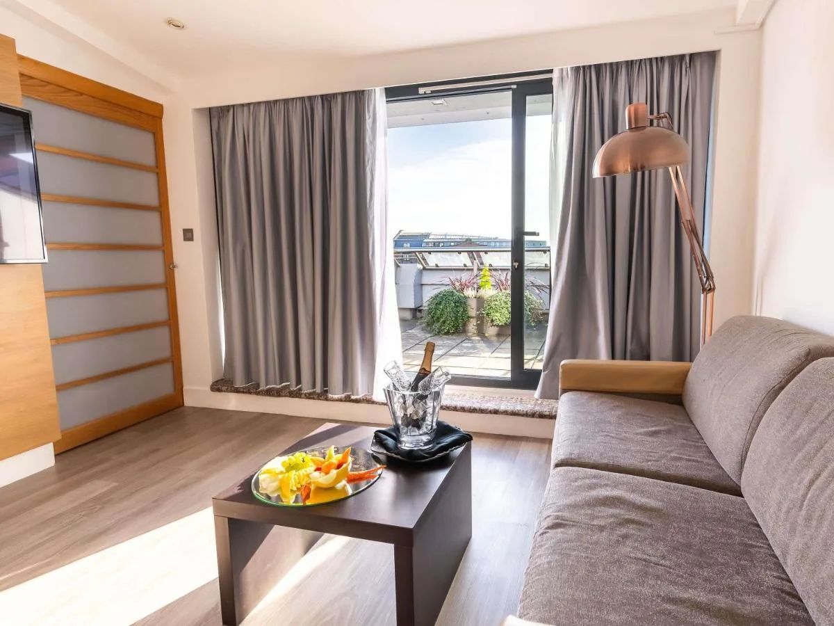 a living room with a couch and a table with a plate of food at Novotel Cardiff Centre in Cardiff