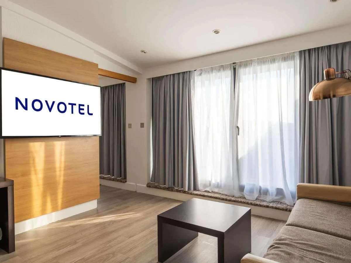 a living room with a couch and a projection screen at Novotel Cardiff Centre in Cardiff