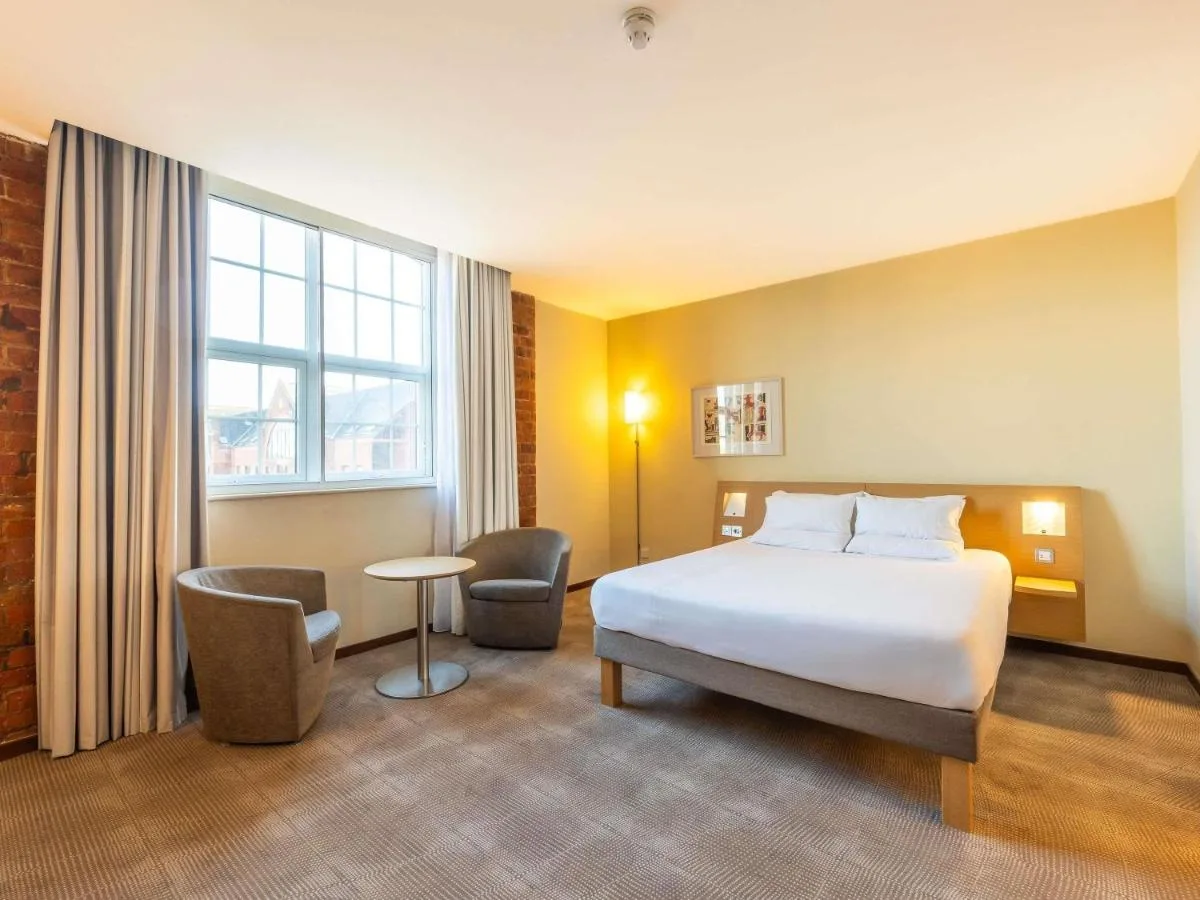 a hotel room with a bed and a table and chairs at Novotel Cardiff Centre in Cardiff